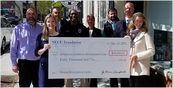 Group of people holding up funding check