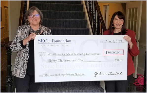 Image of two females holding up funding check