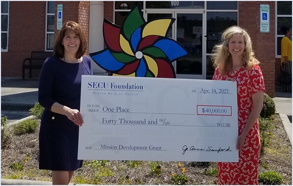 Group of people holding up funding check for One Place