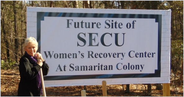 Female standing beside billboard sign